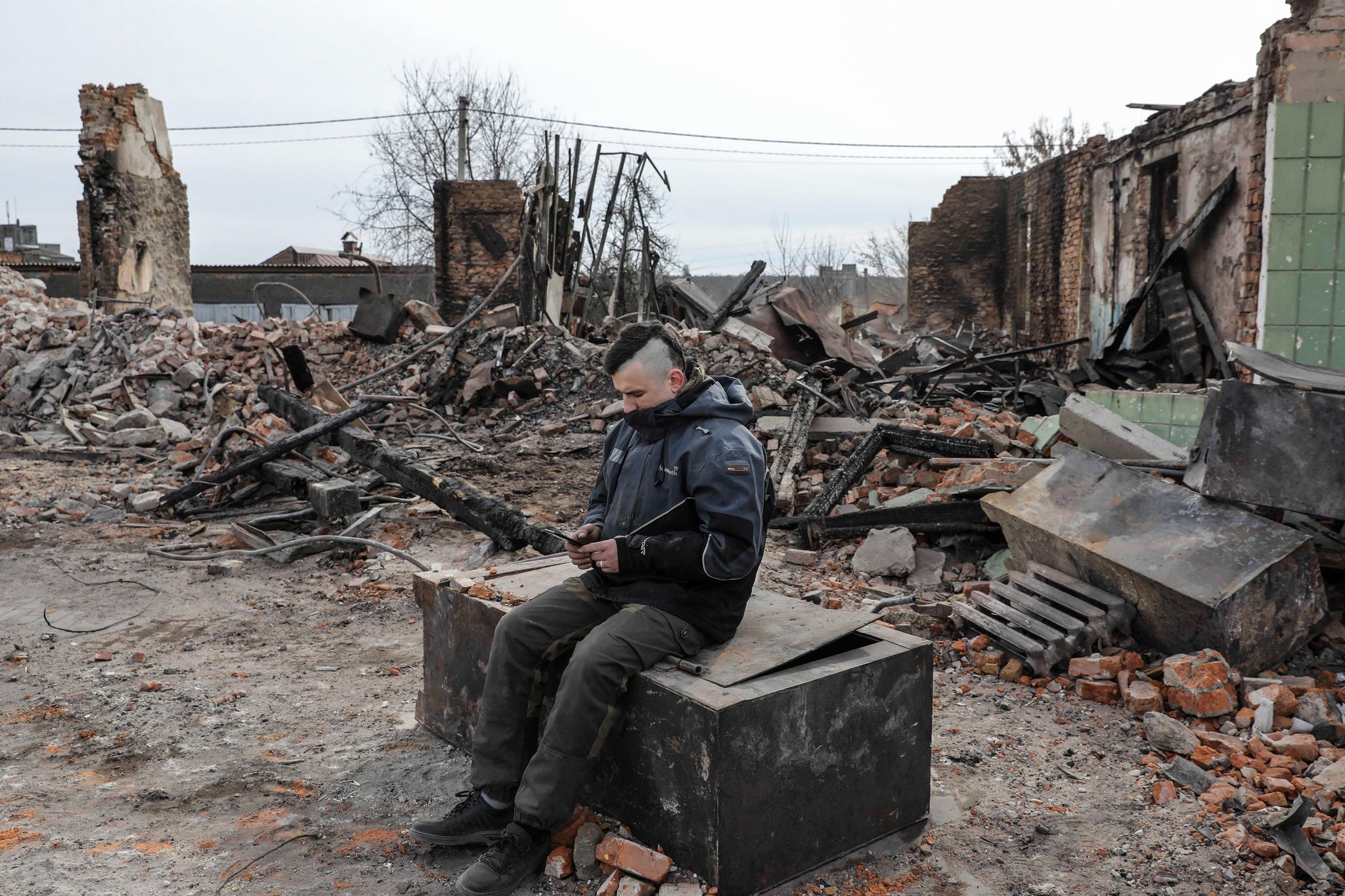 Mies katsoo puhelintaan raunioiden keskellä Ukrainassa.
