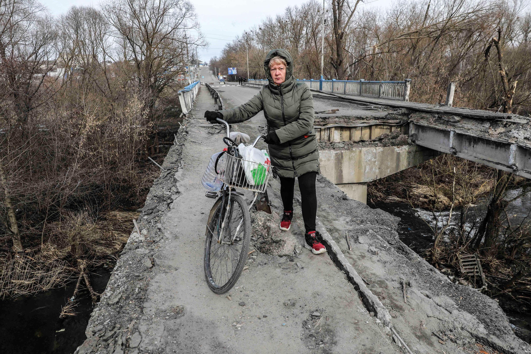 Nainen osin tuhotulla sillalla Ukrainassa.
