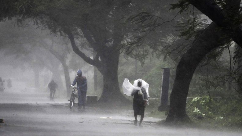 Mies suojaa itseään muovipeitteellä Phailin-syklonia ennakoivissa sateissa Gopalpurissa Intiassa 12.10.2013.