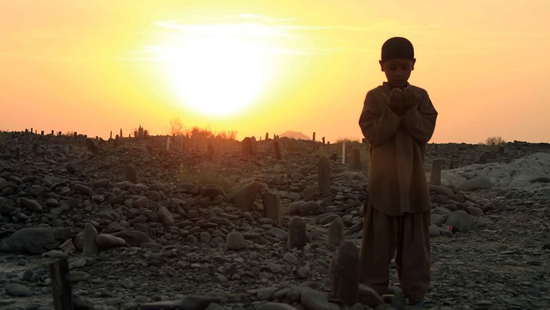 Poika rukoilee maanjäristyksessä kuolleiden sukulaistensa haudalla Balochistanin maakunnassa Pakistanissa.