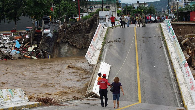 Viranomaiset auttavat ihmisiä ylittämään sortuneen sillan Cocuya de Benítezissä Meksikossa 18.9.2013.