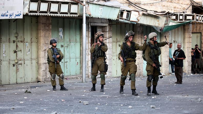  Israeli soldiers take up position during clashes with Palestinian protesters in the West Bank city of Hebron, 27 August 2013. The previous day, three people were killed and six injured after a raid in Qalandiyah, a Palestinian official said.