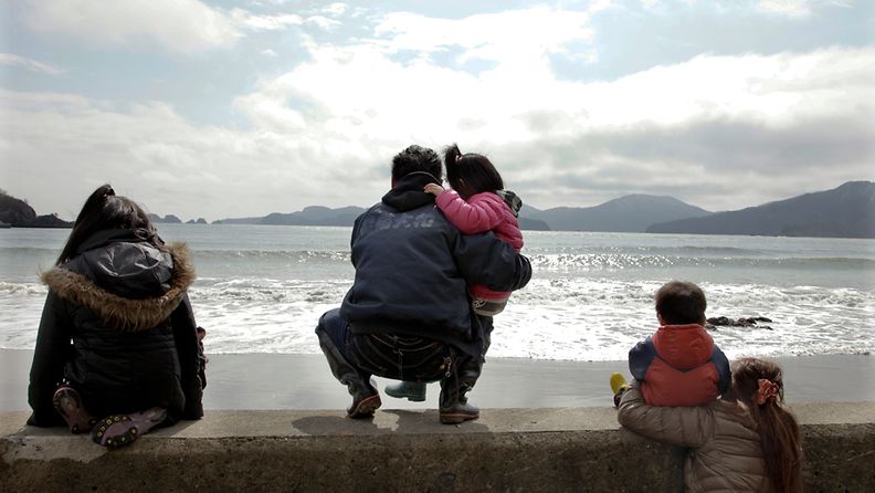 Japanilainen perhe katsoo merelle Kitakami-joen suulla, sadan kilometrin päässä Fukushimasta, maaliskuussa 2012. 