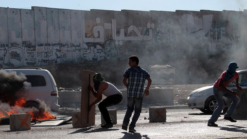 Palestiinalaiset suojautuvat Israelin joukkojen kanssa käytyjen yhteenottojen aikana lähellä Ramallahia 26.8.2013.