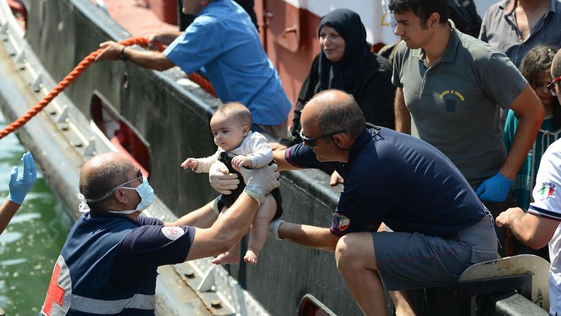 Catanian rannikolla Italiassa Punaisen Ristin työntekijät auttoivat vauvaa laivasta, joka oli täynnä Syyriasta ja Egyptistä paenneita ihmisiä. Kuvattu 19.8.2013.