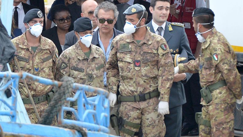 Italian maahanmuuttoministeri Cecile Kyenge (takana aurinkolaseissa) saapui tänään Lampedusan satamaan, jossa hengityssuojaimilla varustautuneet sotilaat siirsivät pakolaisten ruumiita maihin.