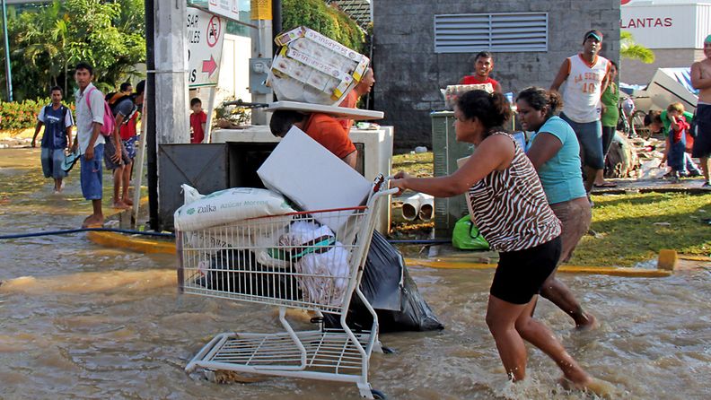 Ihmiset kuljettivat tavaroitaan tulvan alta Acapulcossa Meksikossa 18.9.2013. Hurrikaani Ingrid ja trooppinen myrsky Manuel ovat aiheuttaneet Meksikossa mittavat tulvat. 
