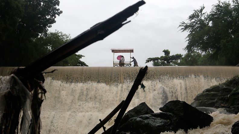 Filipino residents cross on top of an overflowing dam in Las Pinas city, south of Manila, Philippines, 22 September 2013. Typhoon Usagi hit the northern Philippines killing two people and two more missing, uprooting trees, cutting off electricity and forcing hundreds to seek shelter, The National Disaster Risk Reduction and Management Council (NDRRMC) official said. Usagi, with a diameter of 800 kilometres, was expected to move west-northwest at 19 kph and move out of the Philippines on September 22 early morning, barreling towards southern China.
