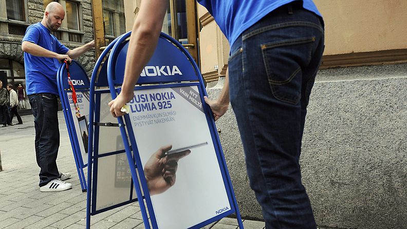 Henkilökunta laittaa Nokia Lumia 925 -älypuhelinta mainostavia kadunvarsimainoksia yhtiön lippulaivamyymälän ulkopuolelle Helsingissä 15. elokuuta 2013.