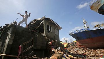 Filippiiniläismies seisoo tuhoutuneen talon katolla Taclobanin kaupungissa Leyten provinssissa 10.11.2013.