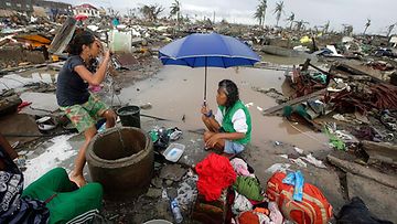 Filippiiniläisnaiset pesevät pyykkiä tuhoutuneiden talojen seassa Taclobanin kaupungissa Leyten provinssissa 10.11.2013.