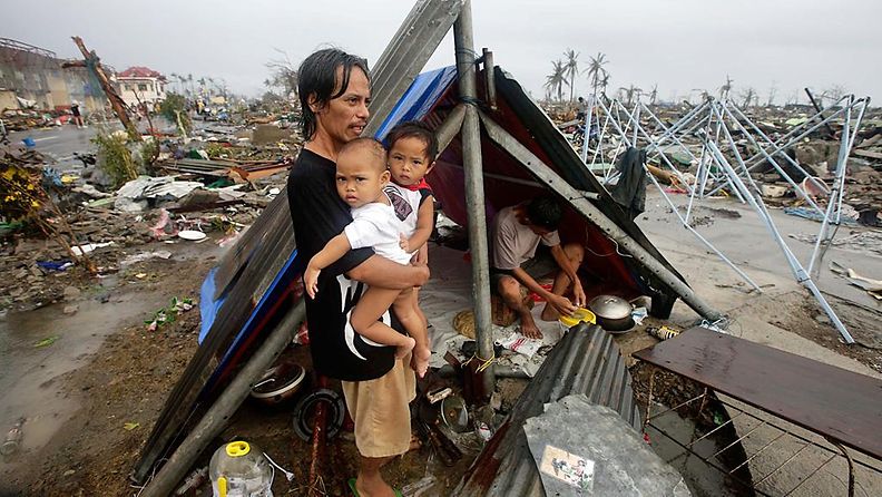 Filippiiniläismies odottaa avustustyöntekijöitä lapsensa kanssa Taclobanin kaupungissa Leyten provinssissa 10.11.2013.