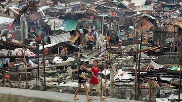 Filippiiniläislapset kävelevät pahoin vaurioituneessa Taclobanin kaupungissa Leyten provinssissa 10.11.2013. 