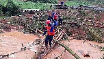 Avustustyöntekijä auttaa perhettä tulvapaikalla Espirito Santon osavaltiossa 23.12.2013.