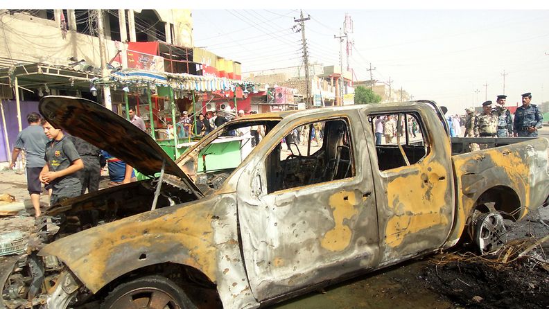 Irakilaispoliisit tutkivat autopommi-iskussa vahingoittunutta autoa Basrassa 20.5.2013. 