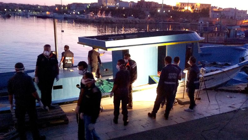 Poliisi ja merivartiosto Lampedusan saaren satamassa pakolaisveneiden vierellä 1.8.2011. Kuva: EPA