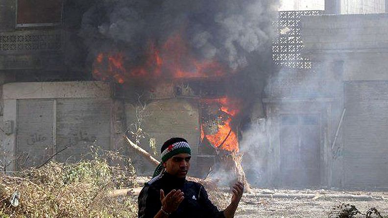Mies seisoo palavan rakennuksen edessä Homsin kaupungissa.