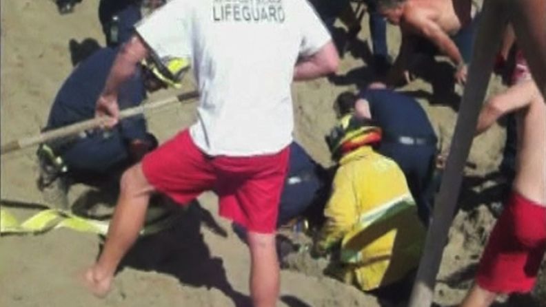 Yhdysvaltalainen teinipoika hautautui kaivamaansa hiekkatunneliin 3.8.2011, mutta selvisi tilanteesta hengissä. Kuvassa pelastushenkilöstö kaivaa poikaa hiekan alta.