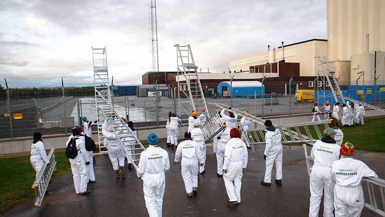 Greenpeacen aktivistit kiipeävät tikkailla Forsmarkin ydinvoimalan aidan yli. Kuva: Greenpeace