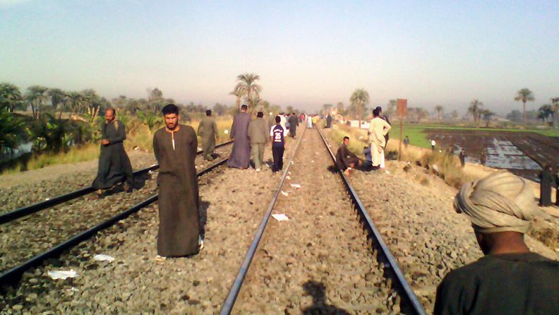 Egyptiläiset kävelevät junaraiteilla lähellä paikkaa, jossa juna törmäsi lapsia kuljettaneeseen linja-autoon  Manfalutin kaupungissa Egyptissä. 