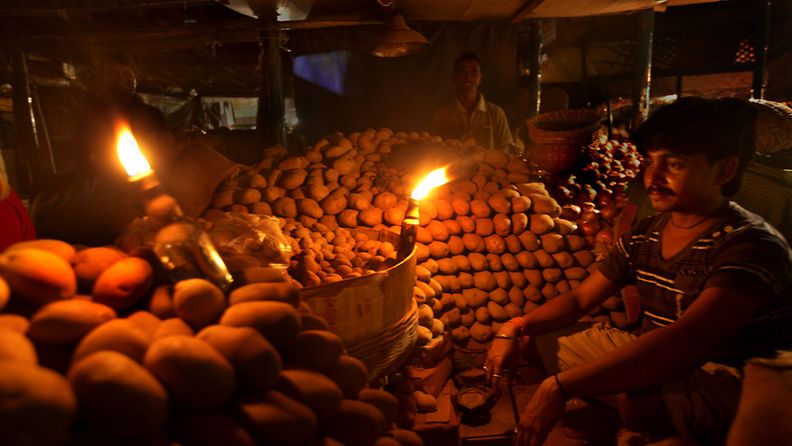 Vihanneskauppias sinnittelee sähkökatkon aikana Kalkuttassa.