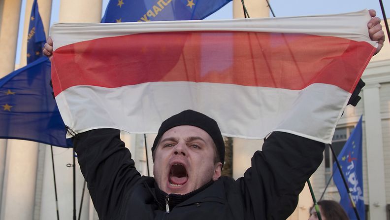 Mielenosoittaja heilutti Valko-Venäjän vanhaa lippua mielenosoituksessa Minskissä 2010.