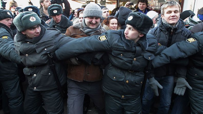 Poliisi pidättelee mielenosoittajaa, joka osallistui Putinin vastaiseen suurmielenosoitukseen Moskovassa.