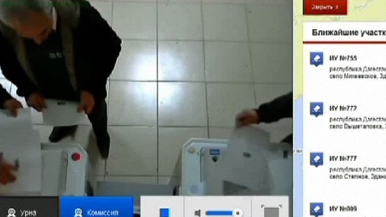 Kuvakaappaus nettivideosta, jossa kaksi miestä syöttää kymmniä ääniä sähköisiin äänestyslippaisiin Venäjällä presidentinvaaleissa 4.3.2012.