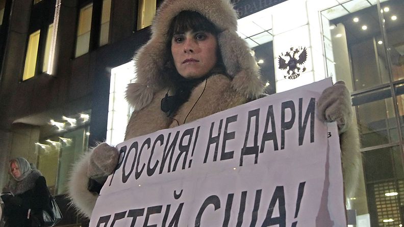 Moskovalaisnainen kantaa kylttiä, jossa lukee: "Venäjä, älä anna lapsiasi Yhdysvaltoihin".