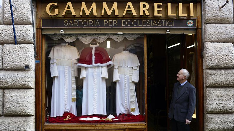 Uuden paavin vaatteet kolmessa koossa räätälinliikkeen ikkunassa.