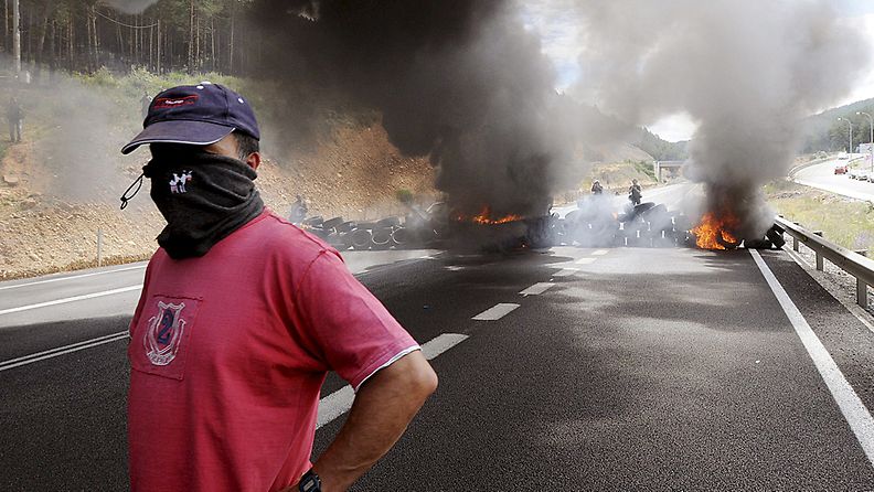 Mielenosoittaja peitti kasvonsa huivilla La Roblan valtatiellä Espanjan Leonissa 20.6.2012.
