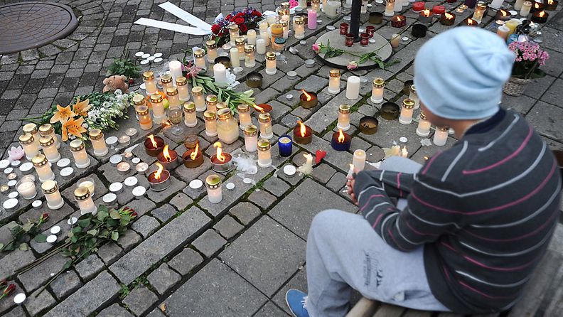 Poika istuu Norjan joukkosurman uhrien muistoksi tuotujen kynttilöiden luona Hønefossin kaupungissa Norjassa 23.7.2011. 
