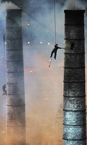 Esiintyjät kiipeävät pitkin savupiippua avajaisseremonian ohjelmassa, joka symboloi teollista vallankumousta.