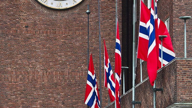 Norjan lippuja puolitangossa Oslon kaupungintalon edessä 23.7.2011.