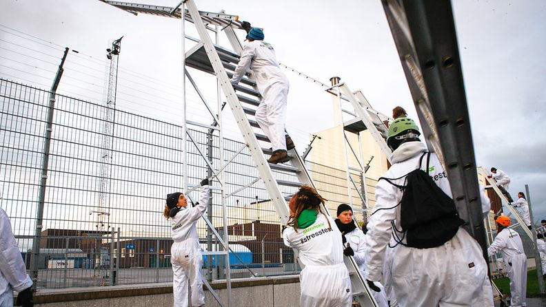 Greenpeacen aktivistit kiipeävät tikkailla Forsmarkin ydinvoimalan aidan yli. Kuva: Greenpeace