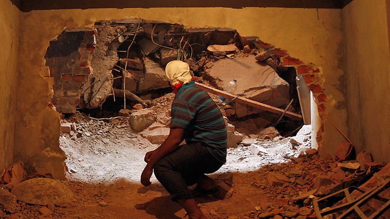 Pelastustyöntekijä katsoo ruumista romahtaneen tehtaan raunioissa Bangladeshissa 26.4.2013.