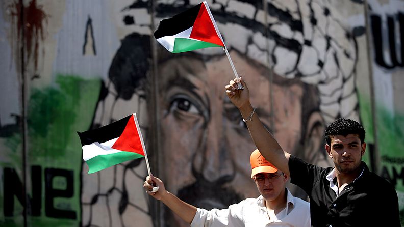 Palestiinalaismiehet lippuineen Yasser Arafatin kuvan edessä 17.9.2011. 