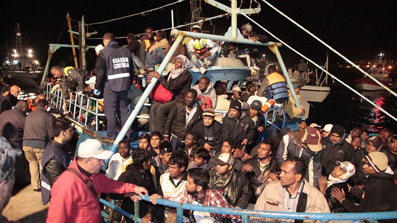  Italian coastguards look on as Libyan refugees arrive on the tiny island of Lampedusa