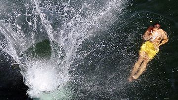 Nuoret miehet hyppäävät Limmat-jokeen Zürichissä Sveitsissä 10.7.2010. Lämpötila on kohonnut eri puolilla maata liki 35 asteeseen. (Kuva: EPA) 