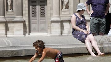 Turistit viilensivät itseään Louvren taidemuseon suihkulähteessä Pariisissa 9.7.2010. Lämpötila on noussut Ranskan pääkaupungissa yli 30 asteeseen.