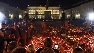 Puolalaiset hiljentyivät suremaan Smolenskin lentoturmassa menehtynyttä presidenttiään Lech Kaczinskyä presidentinpalatsin ulkopuolella Varsovassa 10.4.2010. (EPA)