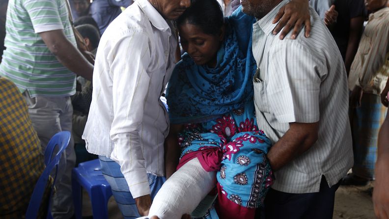 Sukulaiset kantoivat tehdaspalossa loukkaantunutta tekstiitiilityöläistä tämän noutaessa palkkaansa Bangladeshissa. Lähes 900 kuoli tekstiilitehtaan romahdettua Bangladeshissa huhtikuun lopulla.
