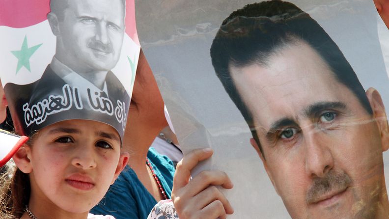 Syyrialaistyttö pitelee käsissään kuvaan maan presidentistä, Bashar al-Assadista. 