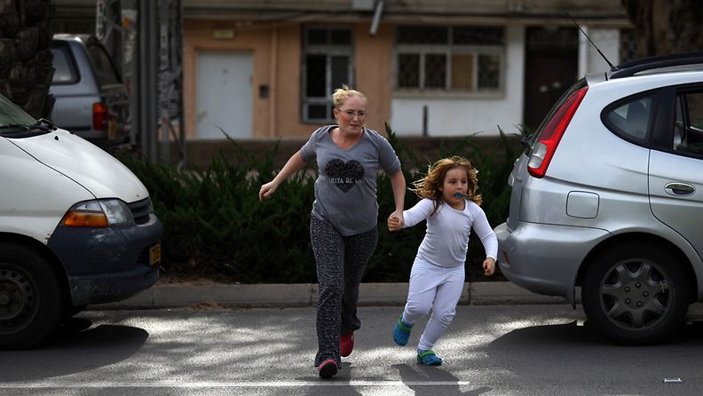Israelilaisnainen juoksee tyttärensä kanssa suojaan Ashkelonin kaupungissa Israelissa. 