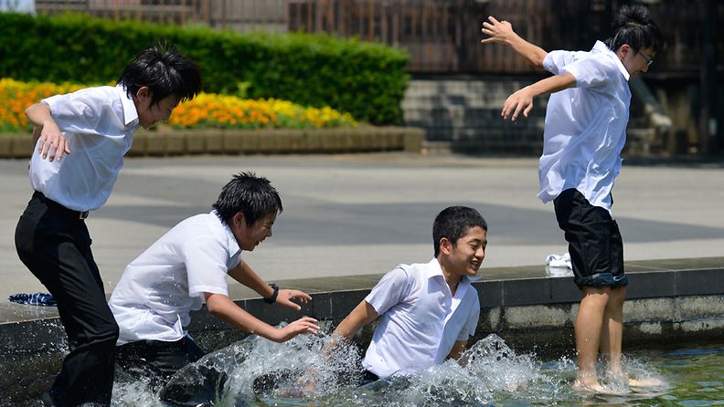 Koululaiset vilvoittelivat suihkulähteessä Tokion keskustassa 8. heinäkuuta 2013.