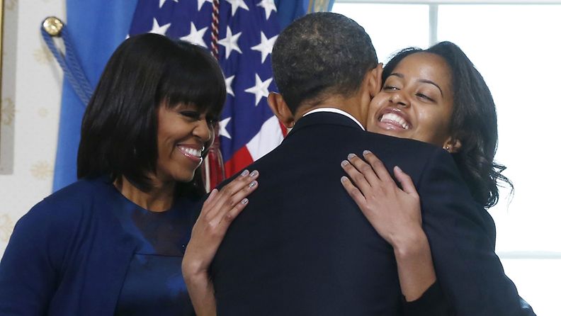 U.S President Barack Obama gets a hug from his daughter Malia as wife Michelle (L) and Sasha looks on in the Blue Room of the White House in Washington, January 20, 2013 after he took the oath of office. EPA/LARRY DOWNING 