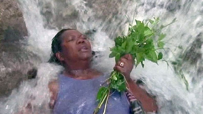 Haitilaisnaisen kädessä olevat mintunlehdet vahvistavat voodoon puhdistautumisrituaalia Saut d'Eaun putouksillla.