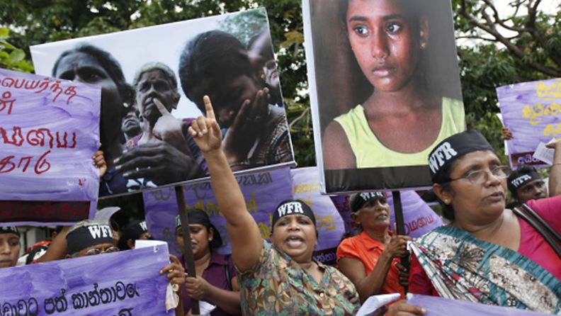 A socialist woman activist shouts slogans during a protest against the rising cost of living and violence against women in Colombo, Sri Lanka, Thursday, March 8, 2012, marking International Women's day. A wave of protests erupted across the island nation during the last weeks after the government increased fuel prices, citing rising world oil prices. Placard on left bottom reads "pay social insurance for women affected by war." (AP Photo/Gemunu Amarasinghe