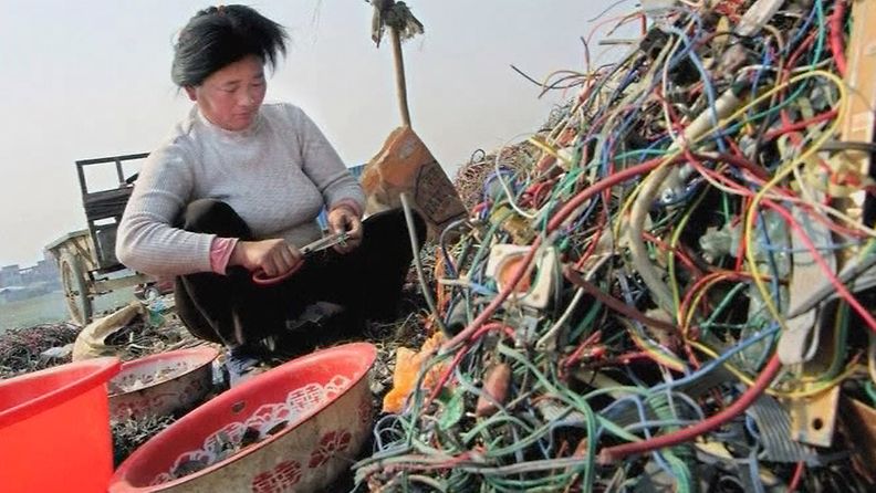 Nainen lajittelee elektroniikkaromusta irrotettuja johtoja Guiyussa, Kiinassa.