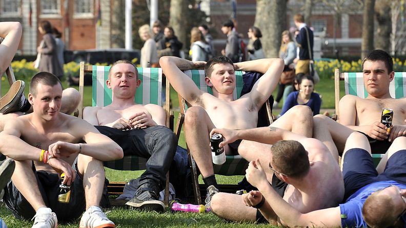 Joukko nuoria miehiä nauttii lämmöstä Lontoossa 23. maaliskuuta 2012.